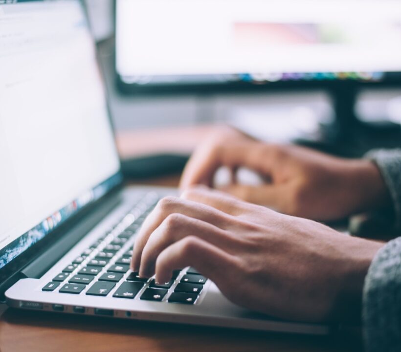 Hands typing on a laptop keyboard on a desk