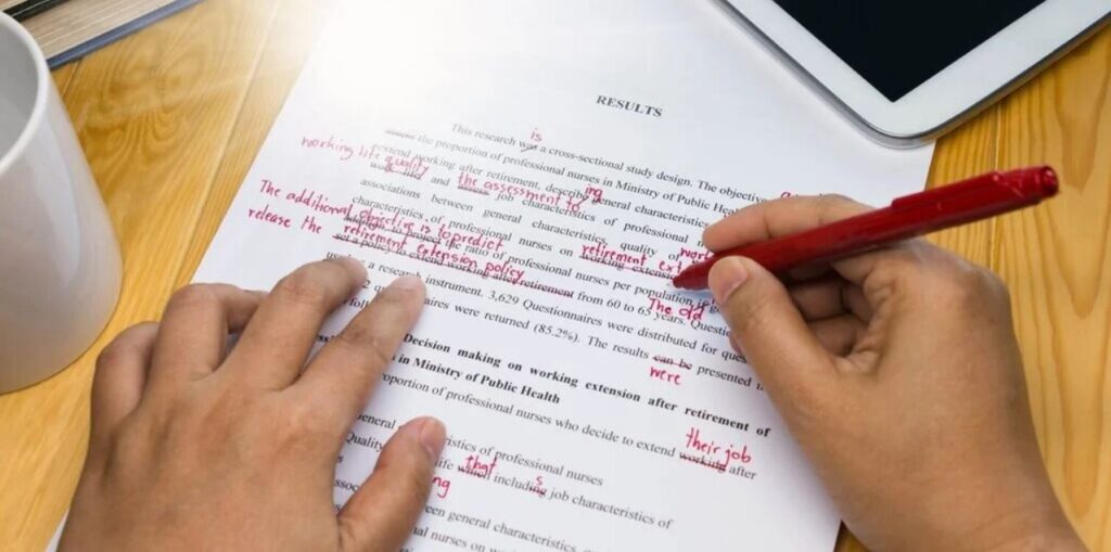copy editor working on document using a red pen to cross out lines and words