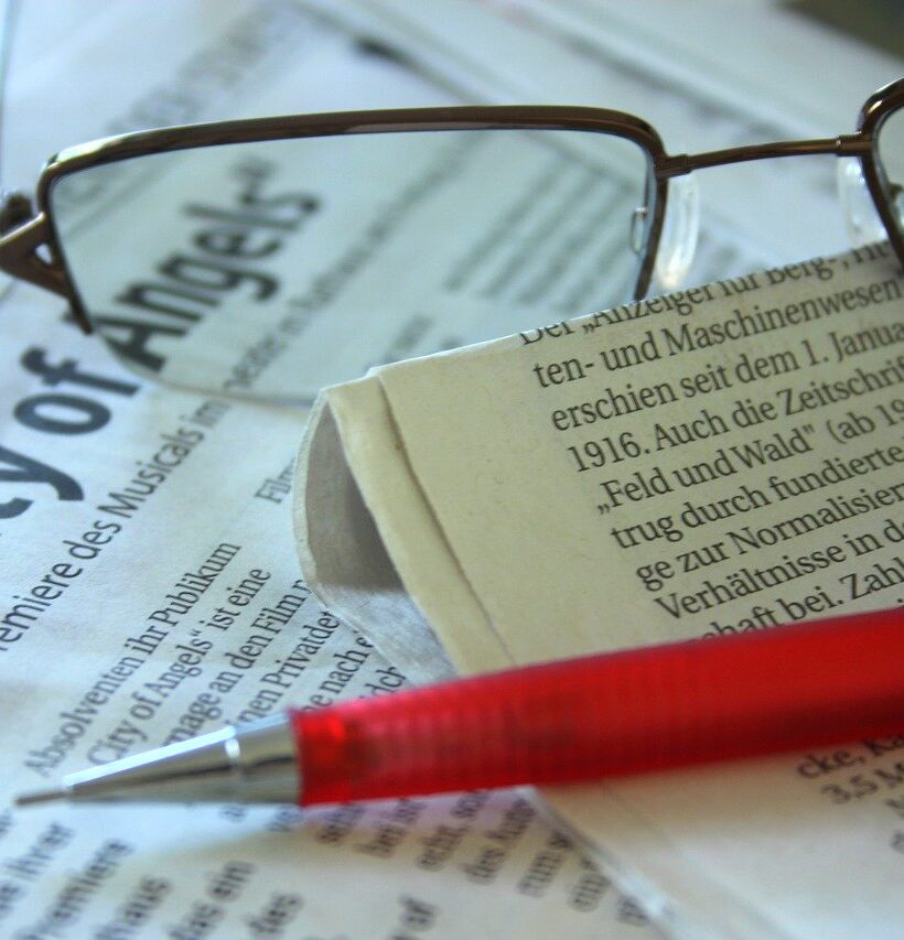 copy-editor-red-pen-on-newspaper-near-glasses